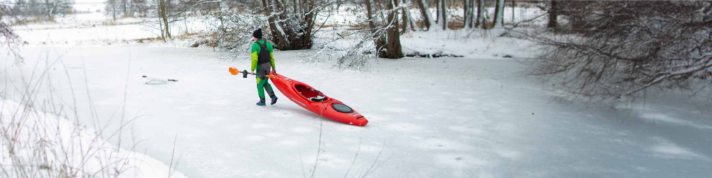 NRS paddler walking on ice, properly dressed for cold-water conditions to prevent hypothermia
