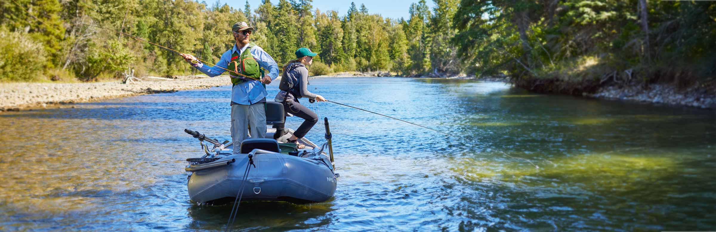 Two anglers wearing fly fishing PFDs while casting from a raft on a river.