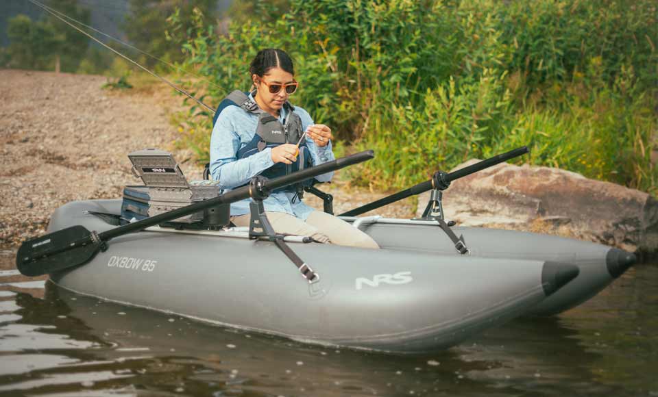 A woman prepares to cast from the lightweight Oxbow 85 Fishing Raft.