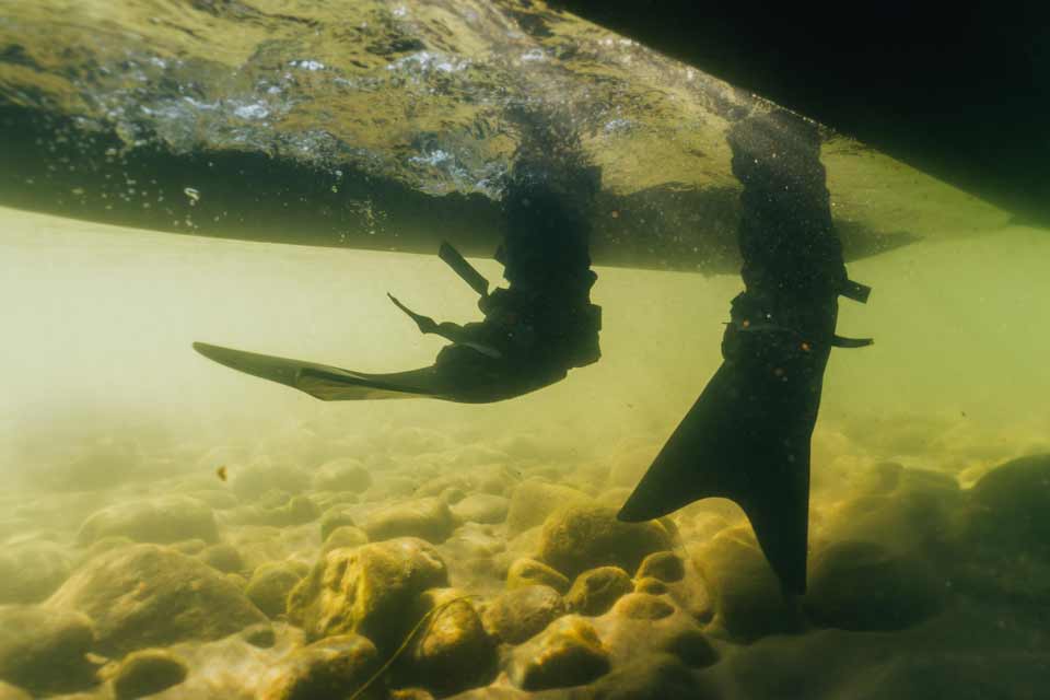 Underwater view of an NRS lightweight fishing raft being propelled by kick fins.