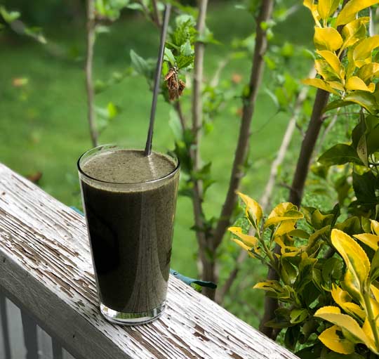 drinking glass with green smoothie and straw