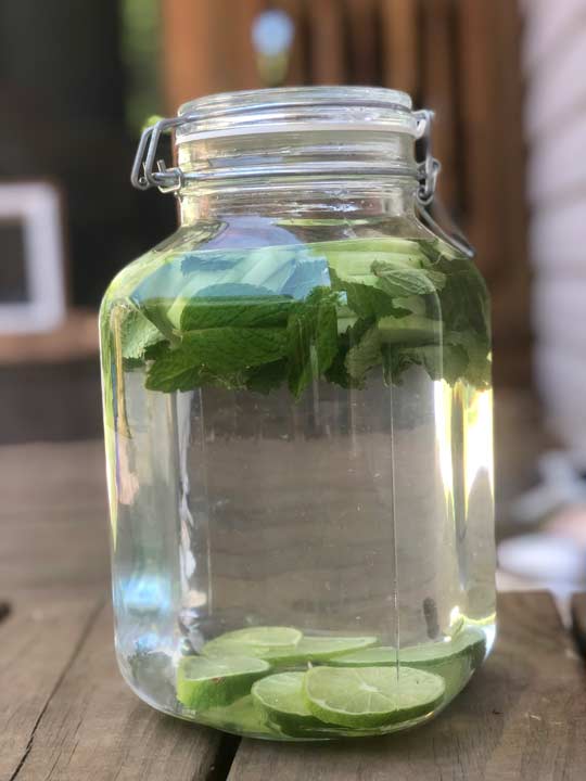 mason jar of water with cucumber slices and mint leaves