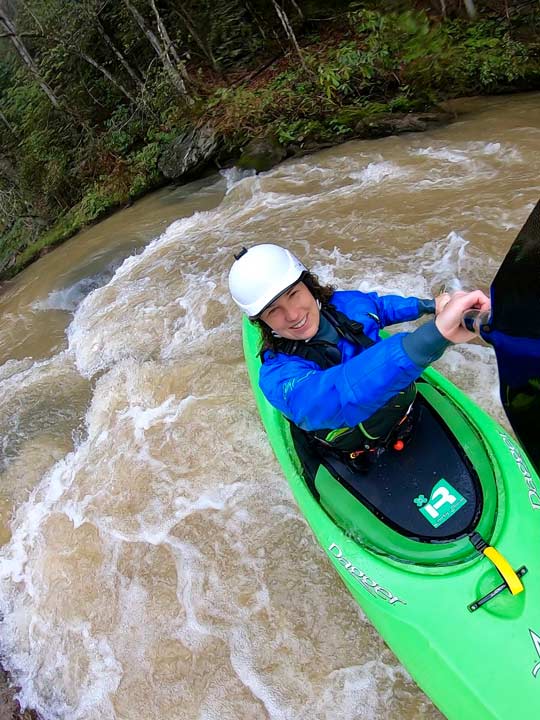 Anna paddling in green kayak.