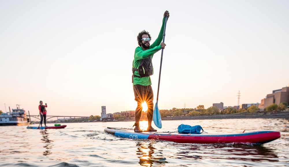 Stand up paddleboarding with city skyline in background.