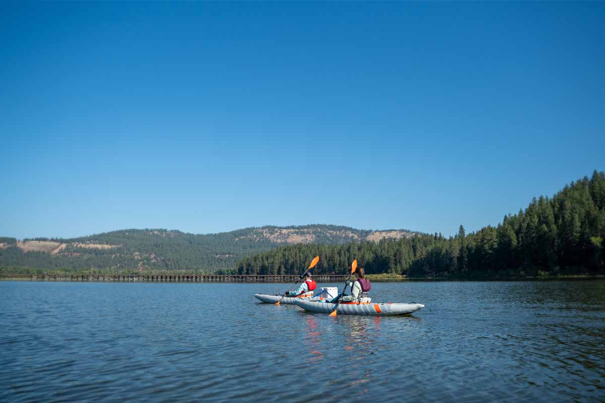 A couple soaks in the sunshine paddling through open water in the Akamai 110 and 125 kayaks.