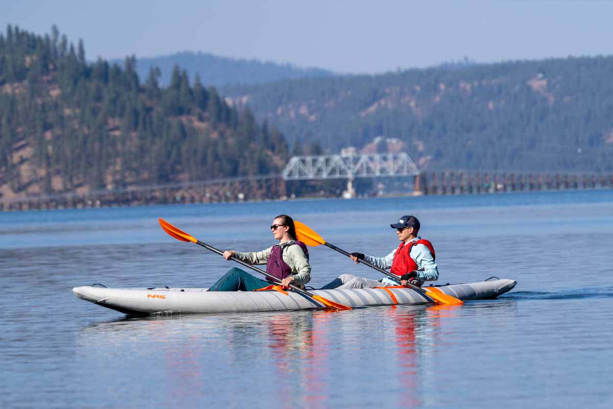 With a bridge passing in the background, a couple makes quick time paddling the Akamai 145 IK downstream. 