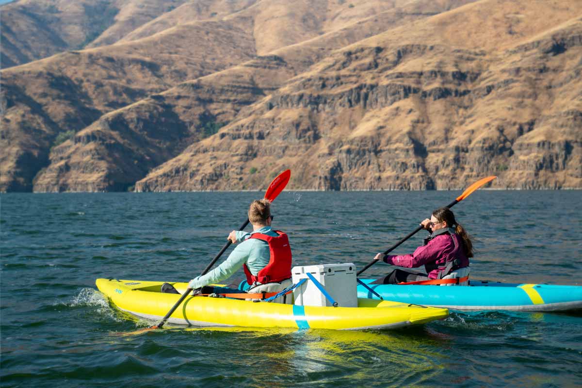 A couple paddles the Kaholo 110 and 125 through open river water.