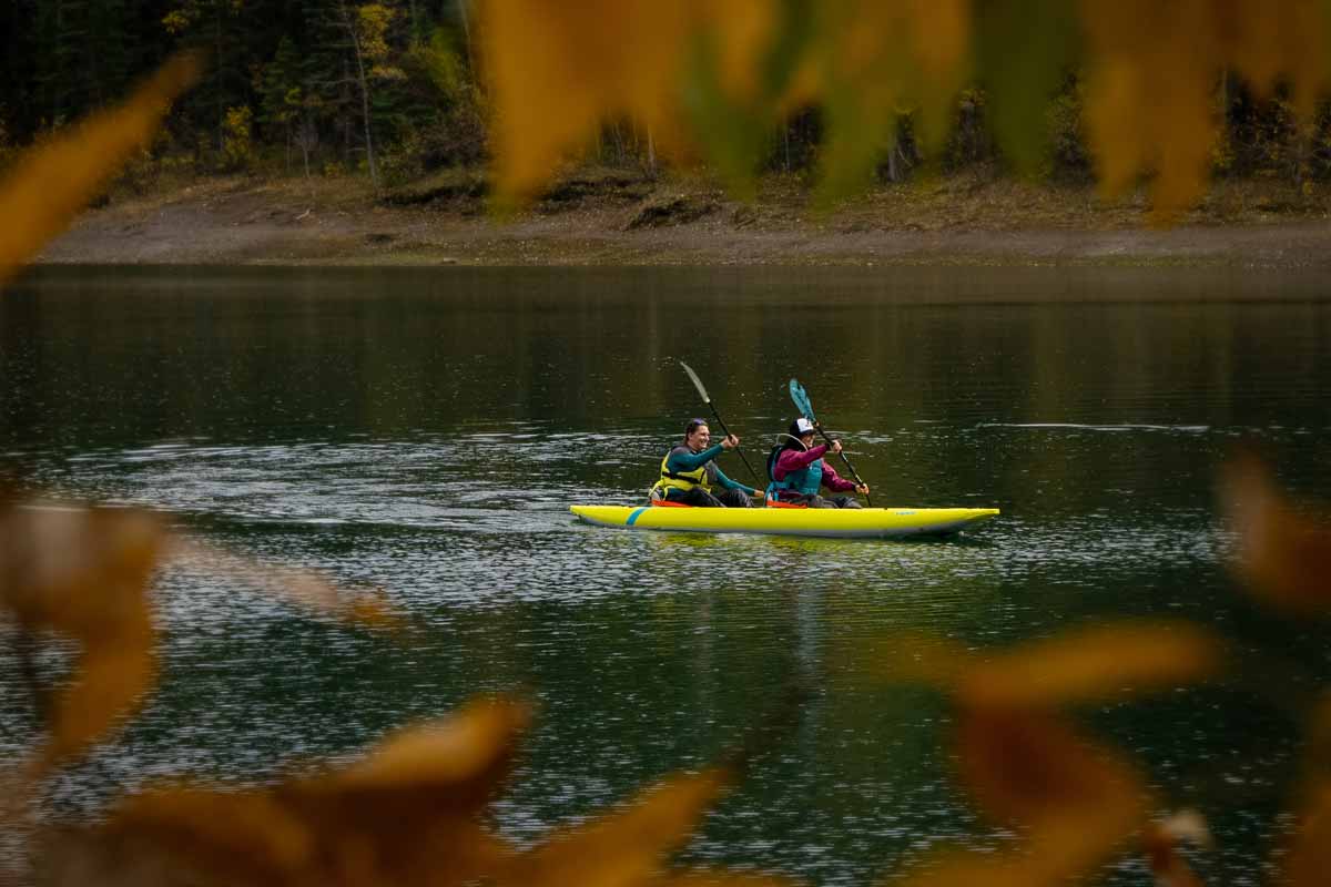 Two paddlers ease through fall colors on the water in the Kaholo 145 inflatable kayak. 