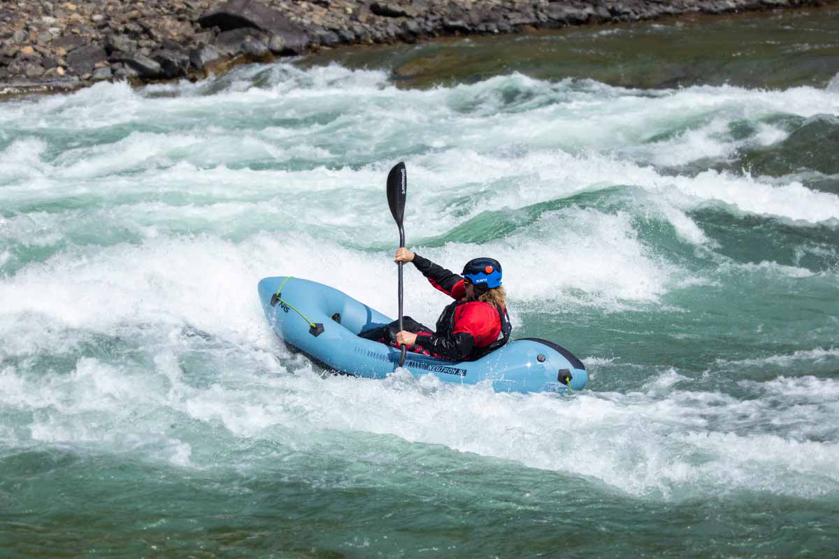 A paddler navigates whitewater rapids in the NRS Neutron SL Packraft.