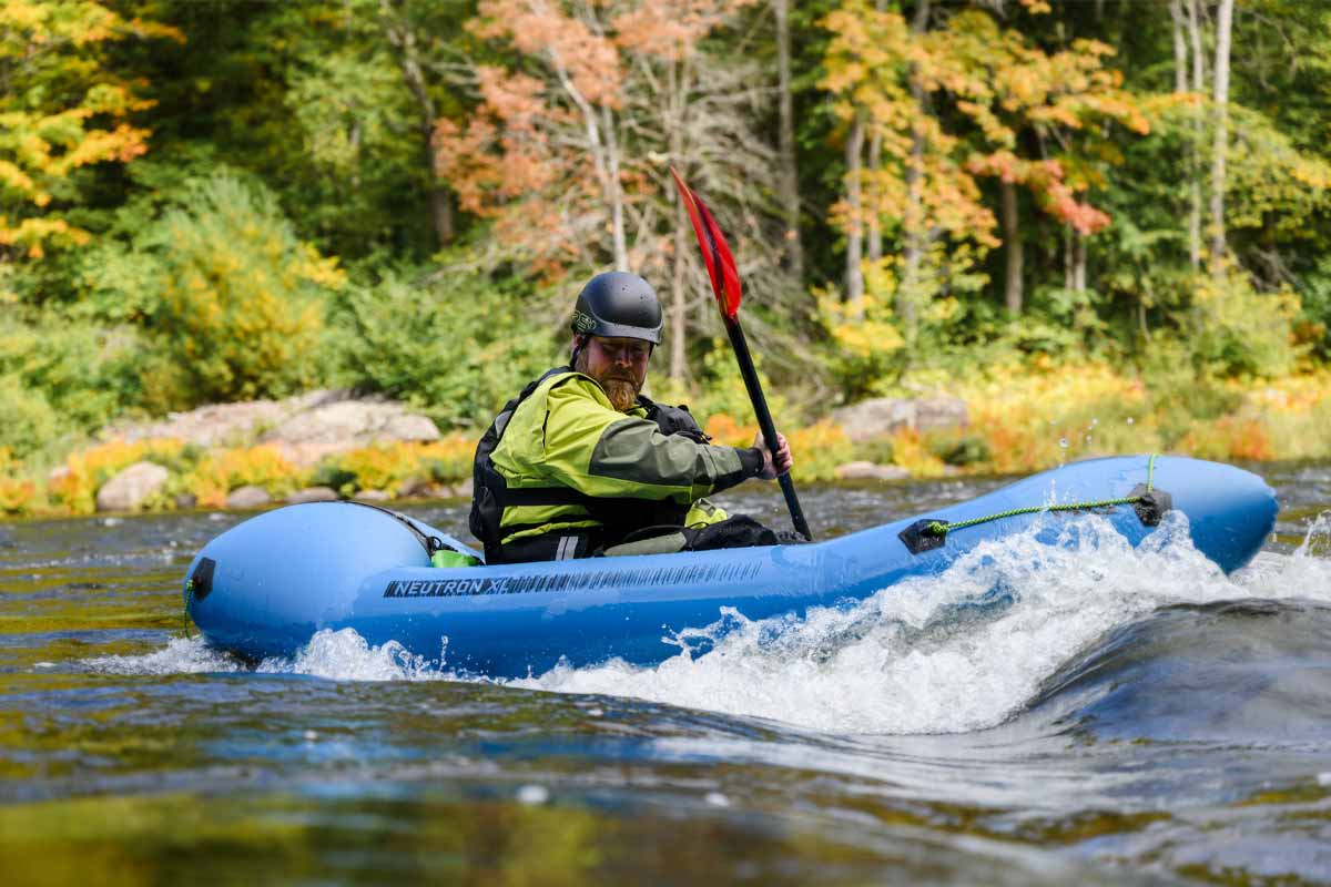 A man catches a wave mid-river in the Neutron XL Packraft.