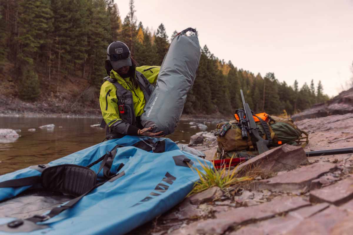 A woman holds the Packraft Internal Storage Bag to stow inside the Orion Packraft.