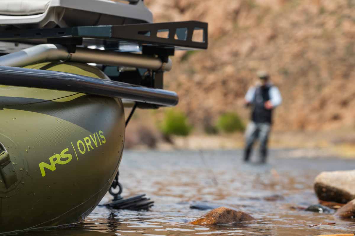 The Orvis Approach raft sits in shallow water while a fisherman wades in the background.