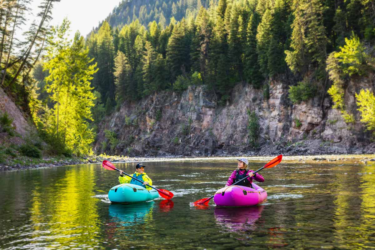 A couple paddles Pulsar packrafts through sunny river waters.