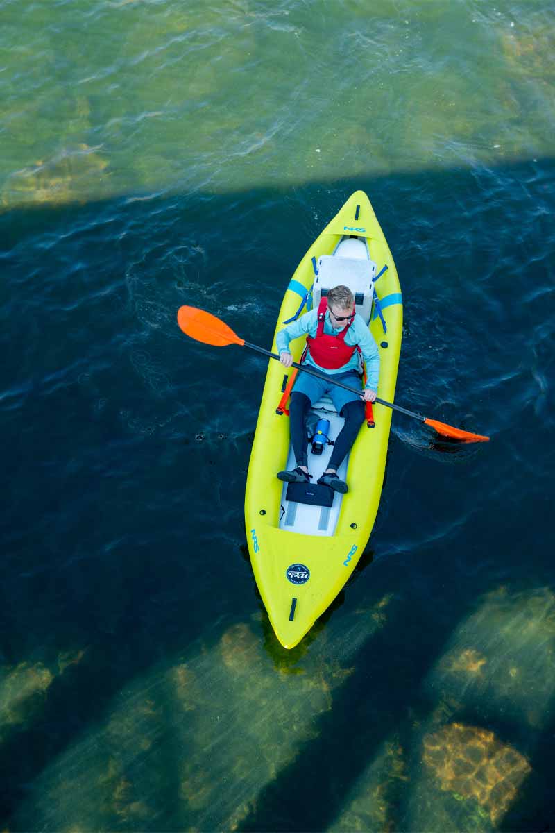 An aerial view shows a man passing under a bridge in the Kaholo 125 inflatable kayak.