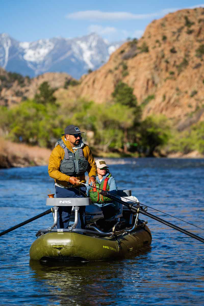 A woman rows the Orvis Approach raft while her partner casts his fishing pole from the bow.